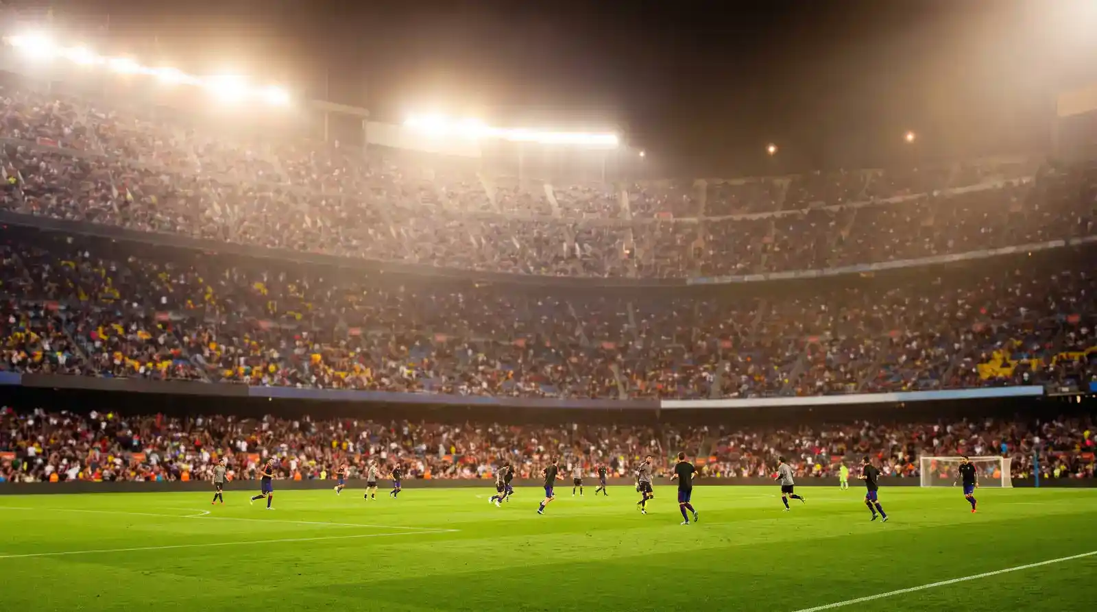 Wide view of a continental football stadium at night under bright floodlights during a major European midweek fixture