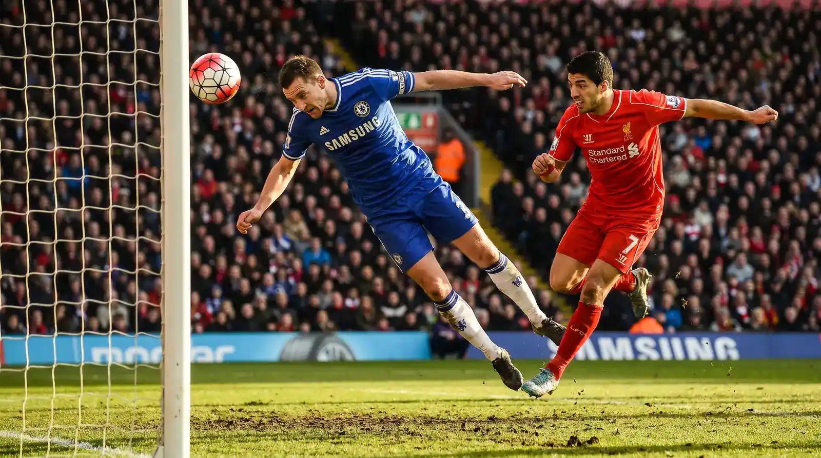 Defender heading away a cross at the near post under pressure during a Premier League fixture