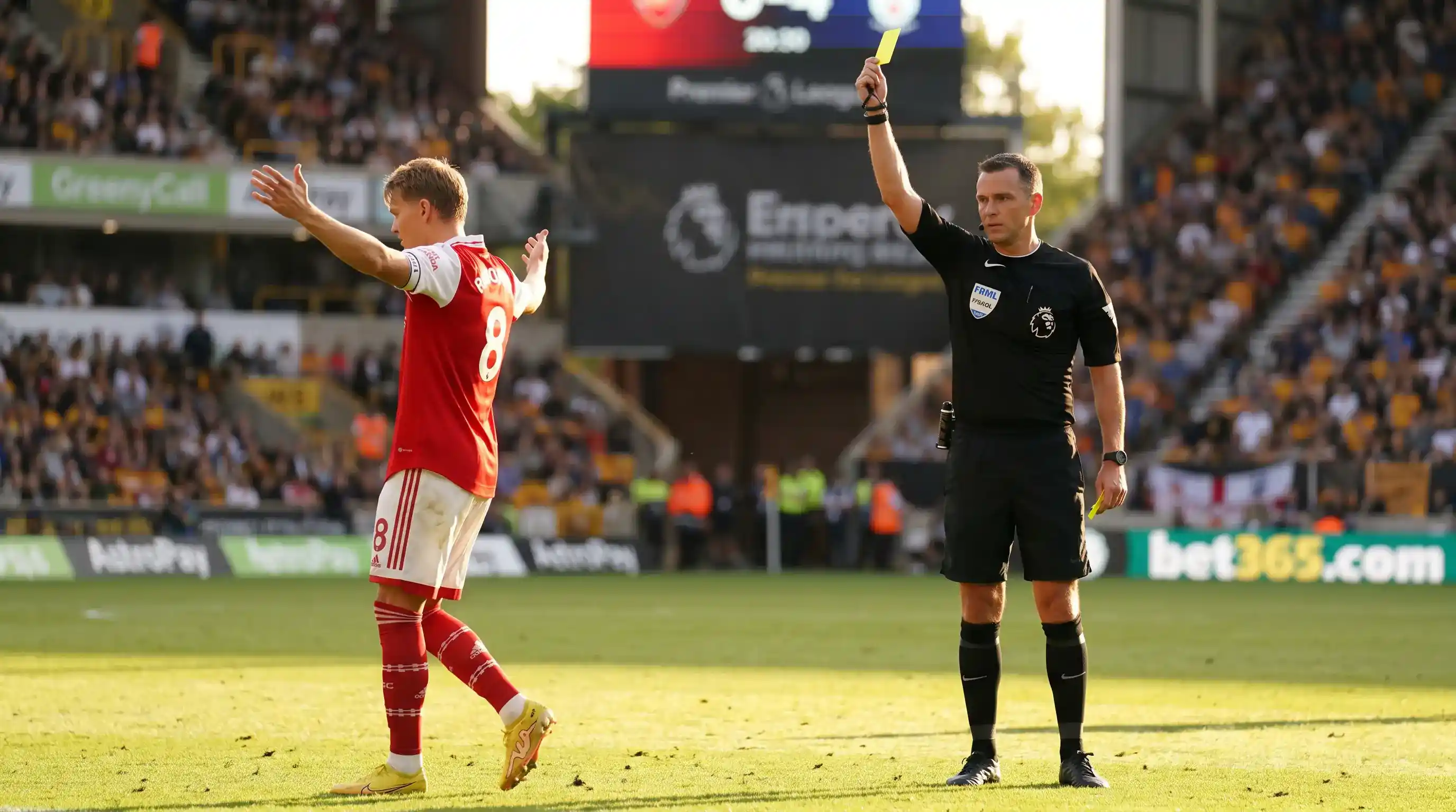 Premier League referee holding a yellow card above his head after booking a midfielder for a tactical foul
